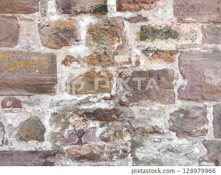 A wall made of stone with a few cracks and some dirt on it 128979966