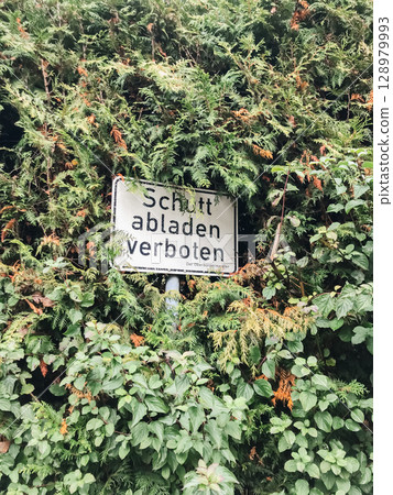 A sign is hidden behind a bush A sign is hidden behind a bush 128979993