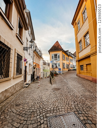 A cobblestone street with a blue sign on the side 128980013