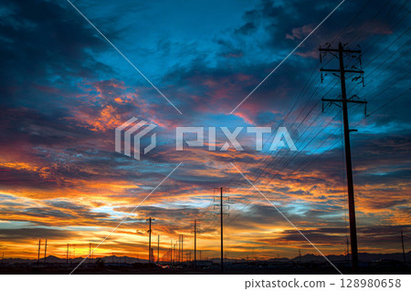 Vibrant Sunset Over Electric Lines and Distant Mountain Landscape. 128980658