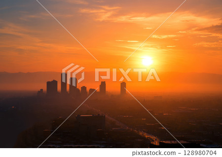 Sunlit Urban Skyline with Warm Orange and Yellow Hues at Sunrise. 128980704