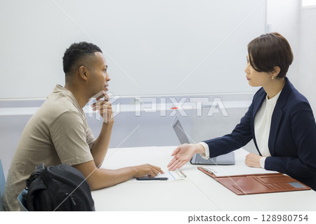 A woman explaining to a foreign man 128980754