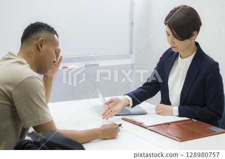 一名女子向一名外國男子解釋 128980757
