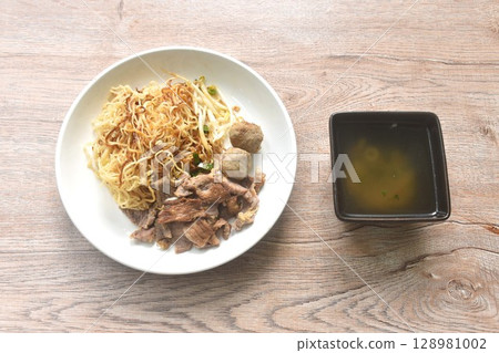 dry boiled Chinese yellow egg noodles with braised beef and meatball dressing black sweet soy sauce on plate with soup dry boiled Chinese yellow egg noodles with braised beef and meatball dressing black sweet soy sauce on plate with soup 128981002