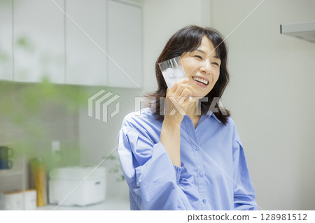 Woman drinking water in the kitchen 128981512