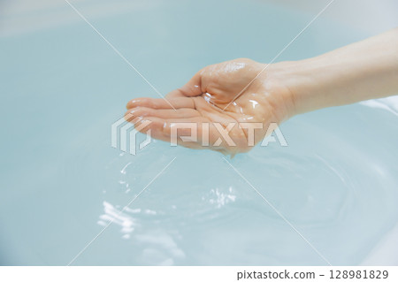 Woman's hand scooping hot water 128981829
