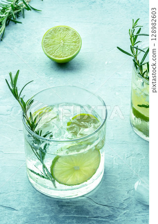Gin tonic, a cocktail of gin with soda, lime, rosemary, and plenty of ice Gin tonic, a cocktail of gin with soda, lime, rosemary, and plenty of ice 128982603