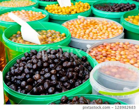 Variety of fresh olives in green buckets at a market stall Variety of fresh olives in green buckets at a market stall 128982683