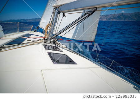 Sailing yacht moving at full speed with all sails up in the open sea near Croatia. Dynamic maritime adventure and freedom of ocean travel. Sailing yacht moving at full speed with all sails up in the open sea near Croatia. Dynamic maritime adventure and freedom of ocean travel. 128983033