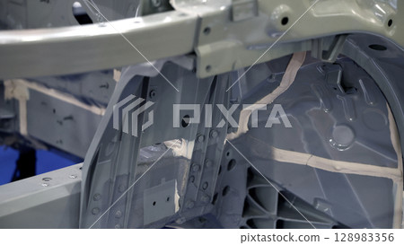 Car body frame. Automotive chassis and interior body frame. Visible weld seams sealant applications and vibration damping sheets. Vehicle chassis structural reinforcement and manufacture precision. 128983356