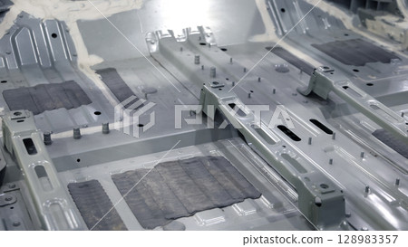 Car body frame. Automotive chassis and interior body frame. Visible weld seams sealant applications and vibration damping sheets. Vehicle chassis structural reinforcement and manufacture precision. 128983357
