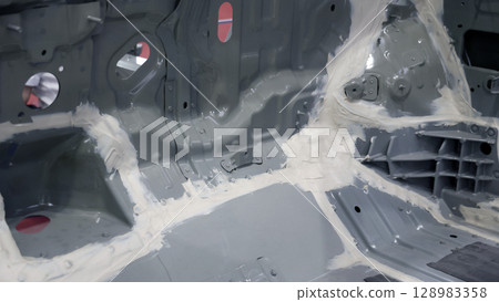 Car body frame. Automotive chassis and interior body frame. Visible weld seams sealant applications and vibration damping sheets. Vehicle chassis structural reinforcement and manufacture precision. 128983358