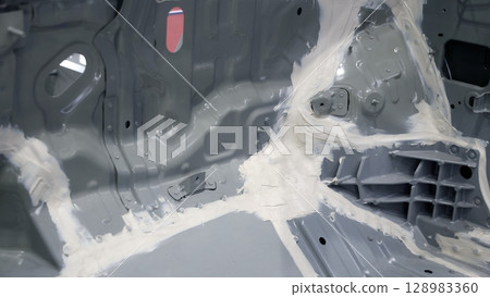 Car body frame. Automotive chassis and interior body frame. Visible weld seams sealant applications and vibration damping sheets. Vehicle chassis structural reinforcement and manufacture precision. 128983360