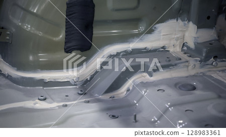Car body frame. Automotive chassis and interior body frame. Visible weld seams sealant applications and vibration damping sheets. Vehicle chassis structural reinforcement and manufacture precision. 128983361