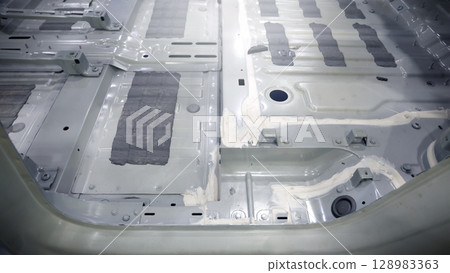 Car body frame. Automotive chassis and interior body frame. Visible weld seams sealant applications and vibration damping sheets. Vehicle chassis structural reinforcement and manufacture precision. 128983363