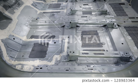 Car body frame. Automotive chassis and interior body frame. Visible weld seams sealant applications and vibration damping sheets. Vehicle chassis structural reinforcement and manufacture precision. 128983364