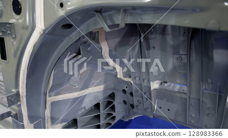 Car body frame. Automotive chassis and interior body frame. Visible weld seams sealant applications and vibration damping sheets. Vehicle chassis structural reinforcement and manufacture precision. 128983366