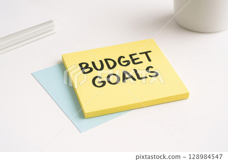 Budget goals written on yellow sticky note with blue paper on white desk symbolizing budget planning and retirement plan for financial success and future security Budget goals written on yellow sticky note with blue paper on white desk symbolizing budget planning and retirement plan for financial success and future security 128984547