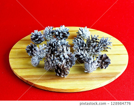 New Year's set for creativity. Natural pine cones painted with silver paint on a wooden board New Year's set for creativity. Natural pine cones painted with silver paint on a wooden board 128984776