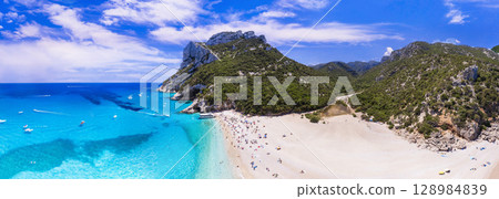 Best and most beautiful beaches of Sardegna island (Italy) - impressive Cala Sisine in gulf of Orosei . Aerial panoramic drone view of white sandy beach and turquoise sea Best and most beautiful beaches of Sardegna island (Italy) - impressive Cala Sisine in gulf of Orosei . Aerial panoramic drone view of white sandy beach and turquoise sea 128984839