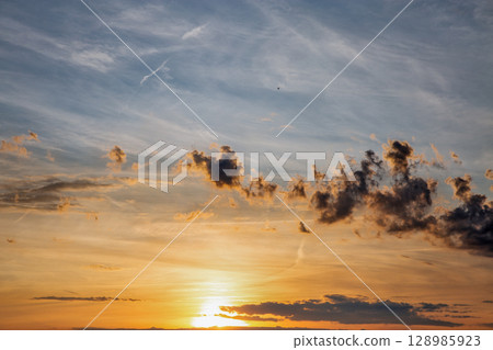 Dramatic sunset sky with scattered clouds 128985923