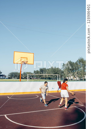 active kids engaged in sport on bright red basketball court with copy space, concept of outdoor activity, children advertisement, school brochure active kids engaged in sport on bright red basketball court with copy space, concept of outdoor activity, children advertisement, school brochure 128986401