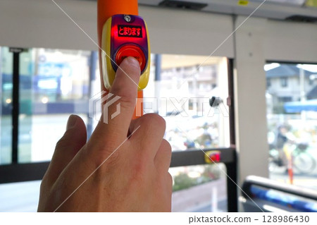 一名男子的手指按下公車上的停車按鈕 一名男子的手指按下公車上的停車按鈕 128986430