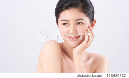 A beautiful young Asian woman with clean, fresh skin against a white background. Skincare, facial treatment, cosmetology, beauty, and spa. An elegant portrait of an Asian woman. A beautiful young Asian woman with clean, fresh skin against a white background. Skincare, facial treatment, cosmetology, beauty, and spa. An elegant portrait of an Asian woman. 128986582