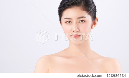 A beautiful young Asian woman with clean, fresh skin against a white background. Skincare, facial treatment, cosmetology, beauty, and spa. An elegant portrait of an Asian woman. 128986584