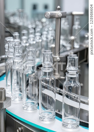 Modern conveyor of a pharmaceutical factory. The movement of ampoules on a conveyor close-up. Modern conveyor of a pharmaceutical factory. The movement of ampoules on a conveyor close-up. 128986604