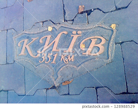 Intricate Kyiv Distance Marker Set into a Cracked Hexagonal Paved Path with Leaves 128988529