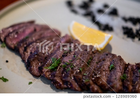 Medium rare picanha meat served on plate with lemon and black truffle paste 128989360