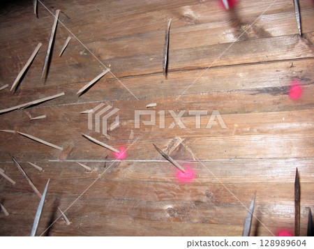A wooden floor scattered with sharp spikes and red stains, set in a stone walled room, creating a menacing historical punishment scene A wooden floor scattered with sharp spikes and red stains, set in a stone walled room, creating a menacing historical punishment scene 128989604