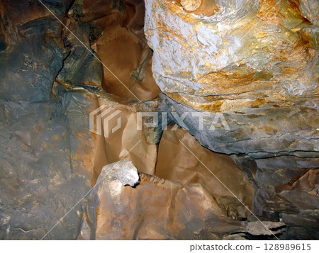A cave interior with smooth, flowing rock formations in earthy tones, showcasing a serene underground geological landscape with subtle lighting A cave interior with smooth, flowing rock formations in earthy tones, showcasing a serene underground geological landscape with subtle lighting 128989615