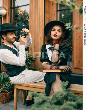 Woman holding red book looking into distance beside man with vintage camera 128989679