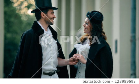 Smiling couple in vintage costume holding hands outdoors 128989692