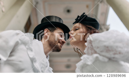 Man and woman in period clothing stand face to face under classical arch Man and woman in period clothing stand face to face under classical arch 128989696