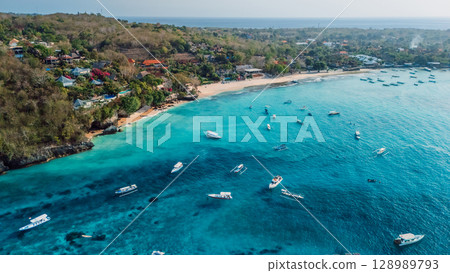 Nusa Lembongan with tropical beach coastline and turquoise ocean with boats, above view Nusa Lembongan with tropical beach coastline and turquoise ocean with boats, above view 128989793