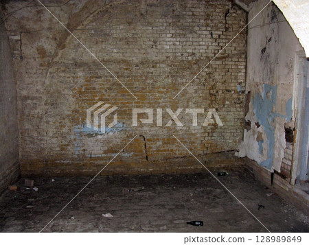 A derelict brick room with peeling walls and scattered debris on the floor, featuring an arched ceiling in a forgotten historical space A derelict brick room with peeling walls and scattered debris on the floor, featuring an arched ceiling in a forgotten historical space 128989849