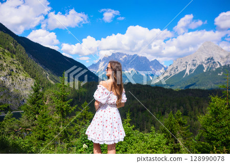 Woman in white dress gazing at mountains 128990078