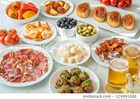 Spanish Tapas Spread with Jamon, Cheese, Shrimp, Olives, and Chilled Beer 128991888
