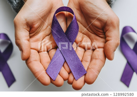 Cupped hands gently present a vibrant purple awareness ribbon, symbolizing world cancer support and global hope for a healthier future. 128992580