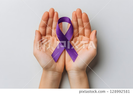 Hands gently present a vibrant purple ribbon, symbolizing universal cancer awareness and crucial support for global health initiatives. 128992581