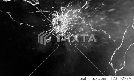 Close-up of gunshot through the glass, shattering against the black background Close-up of gunshot through the glass, shattering against the black background 128992759