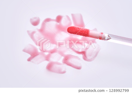 A pink lip gloss brush with a texture on the background. A pink lip gloss brush with a texture on the background. 128992799