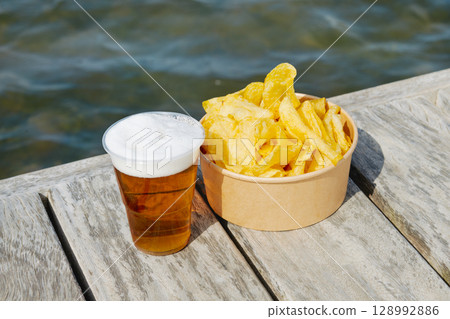 cup of beer and potato chips on a wooden dock 128992886
