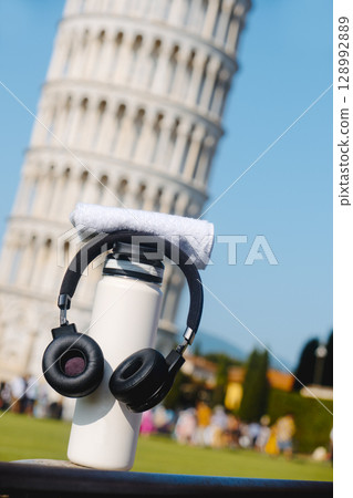 bottle and headphones by the Tower of Pisa 128992889
