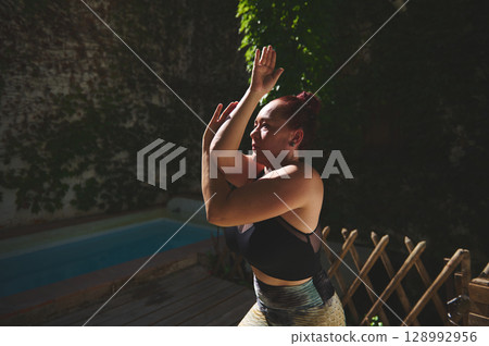 Fit Woman Practicing Yoga Outdoors in Sunlight on a Wooden Deck 128992956