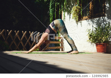 Woman Practicing Yoga Outdoors in a Peaceful and Serene Garden Setting on a Sunny Day 128992985