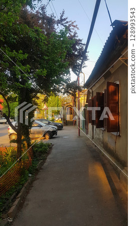 Evening Sunlight on Old Building Shutters, Sidewalk, and Cars 128993543
